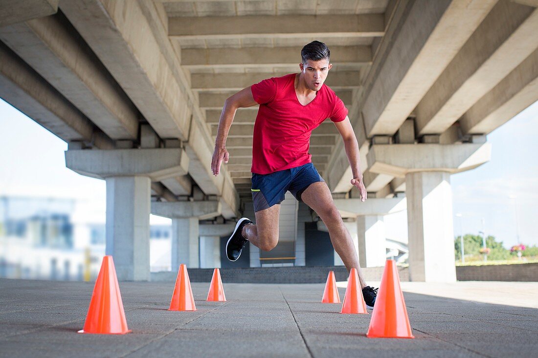 Young men running around plastic cones