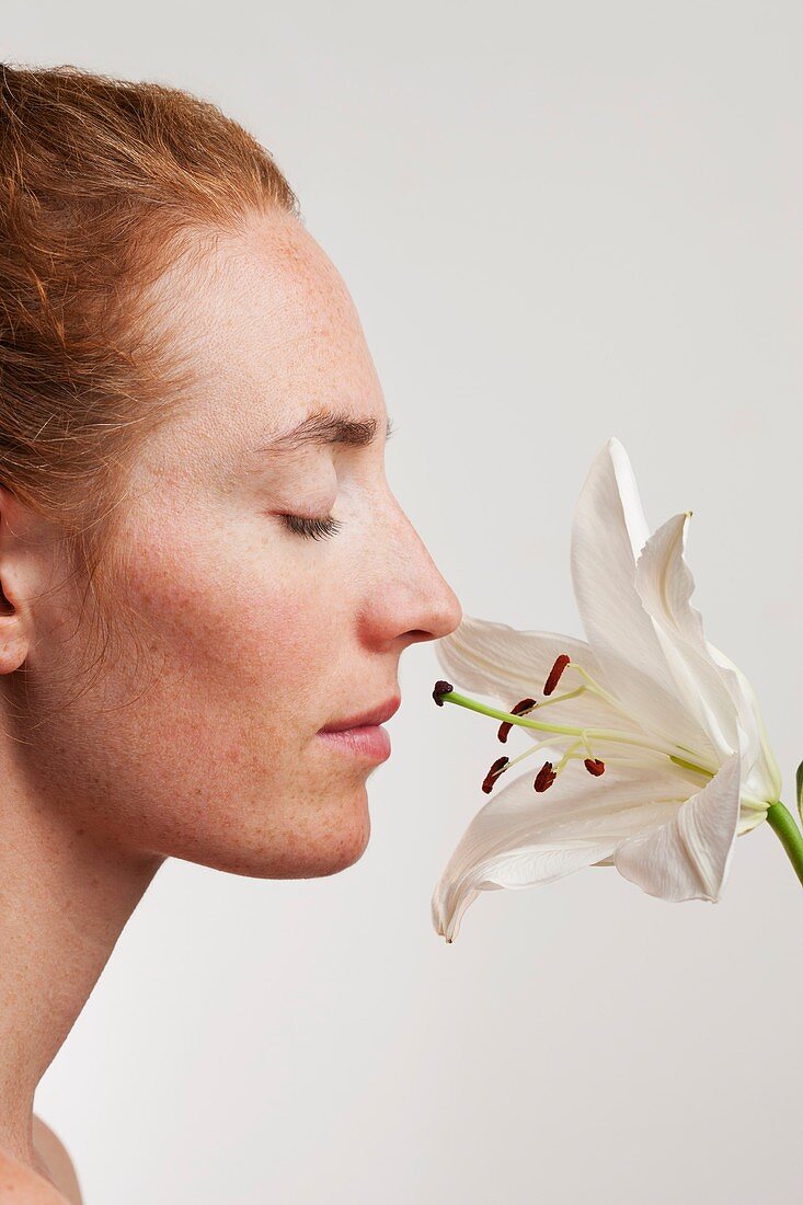 Woman smelling white lily flower