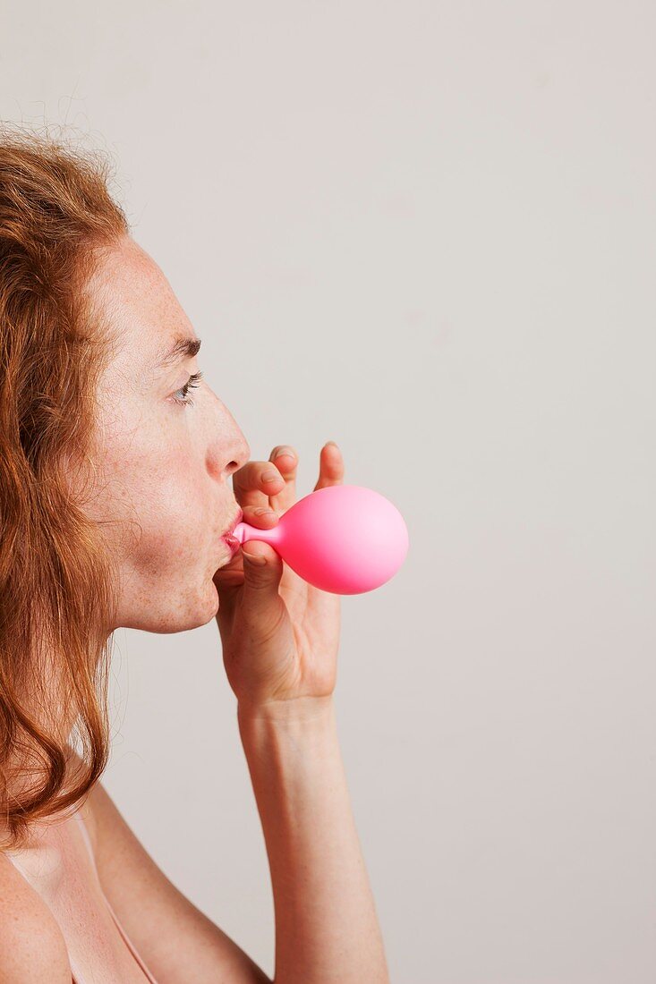Woman blowing up pink balloon