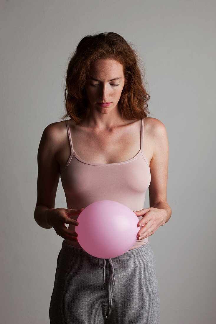 Young woman holding inflated balloon