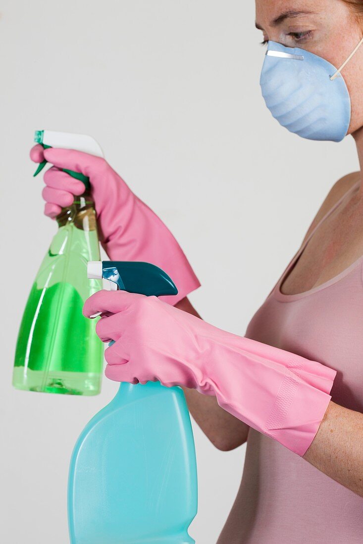 Woman wearing face mask holding cleaning materials