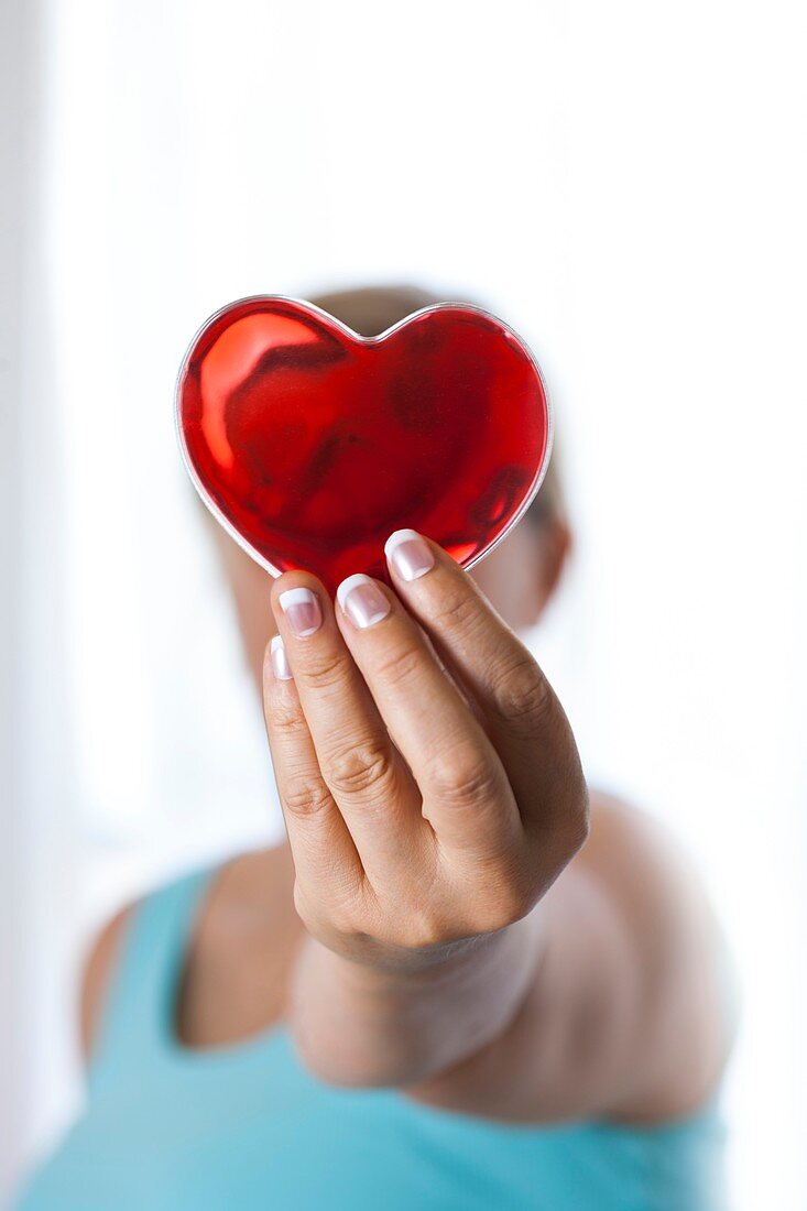 Woman holding red heart in front of her face