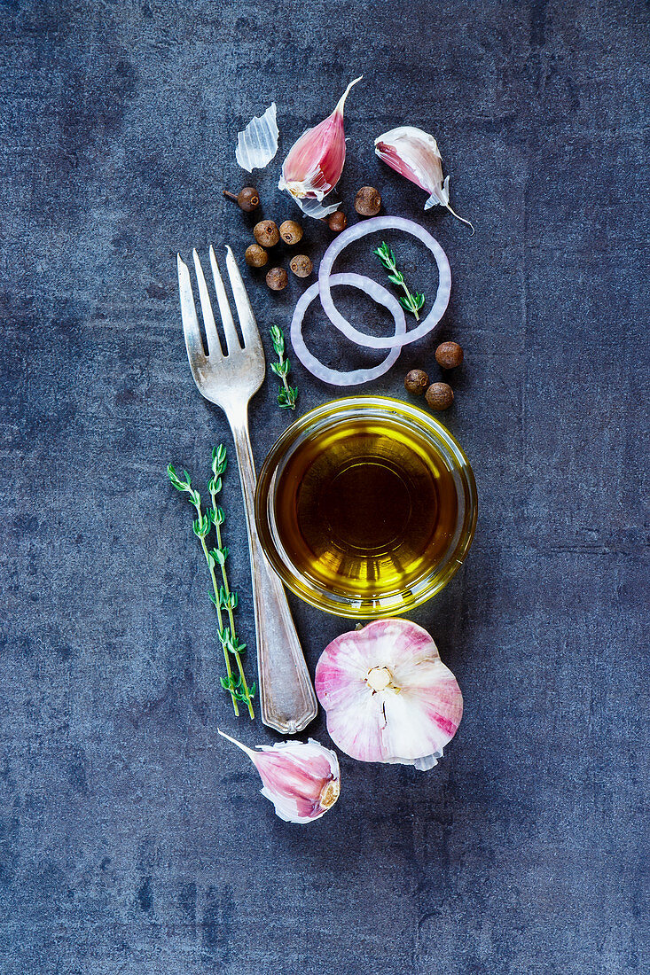 Vintage background with cooking ingredients (olive oil, onion, garlic) on dark metal texture