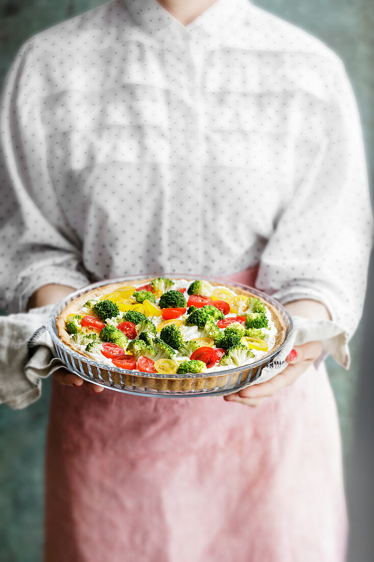 A woman holding a low-carb vegetable quiche