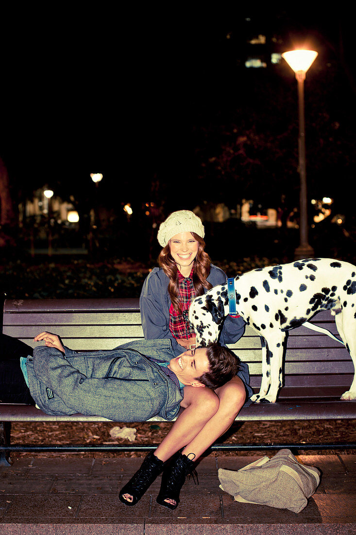 A young couple with a Dalmatian on a bench