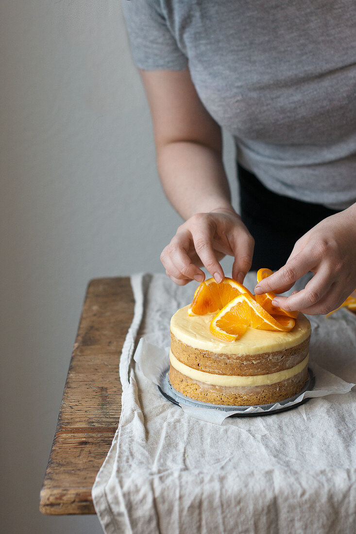 A layered orange cake decorated with sliced oranges