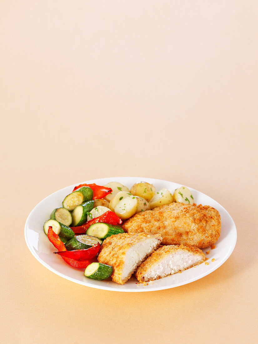 Breaded chicken steaks with potatoes, zucchini and peppers