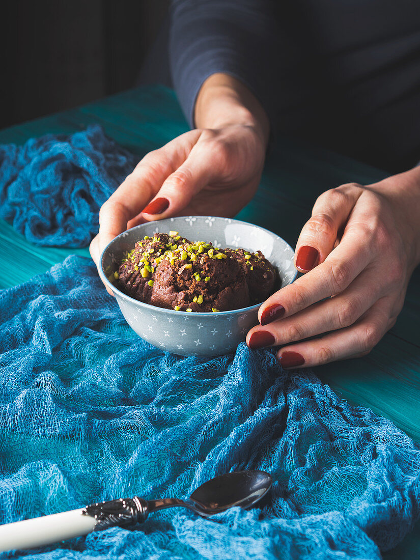 Woman holding a bowl with raw dessert made of nuts and dark chocolate