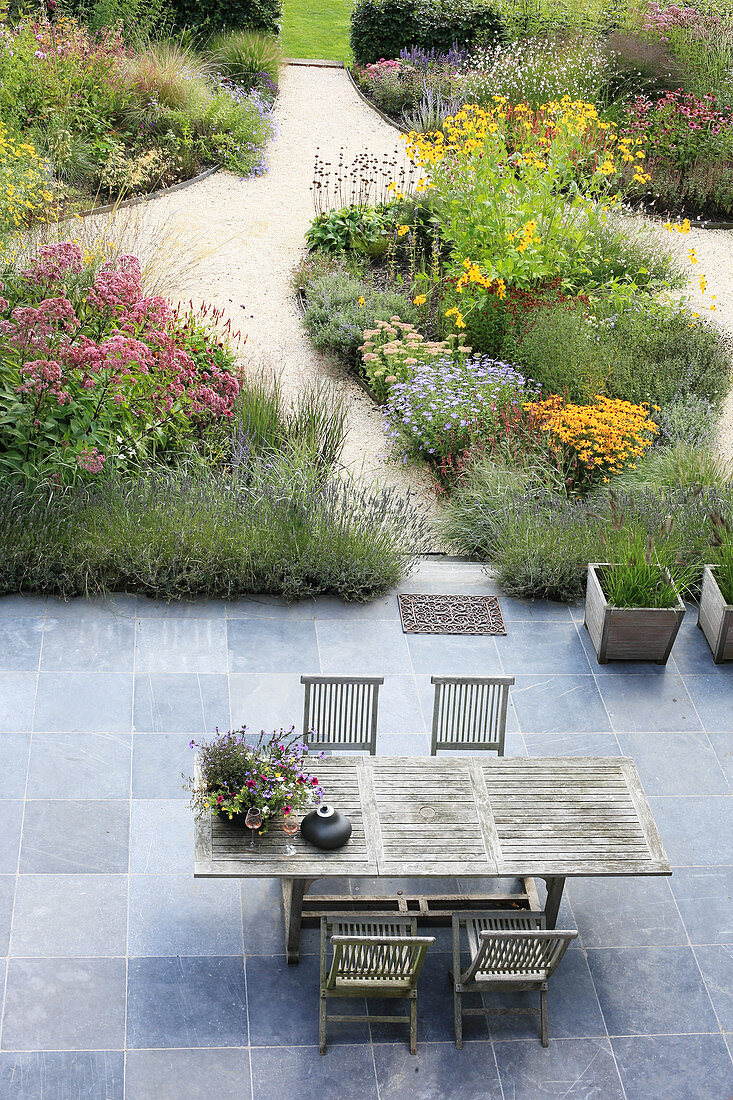 View down onto garden furniture on terrace adjoining herbaceous borders