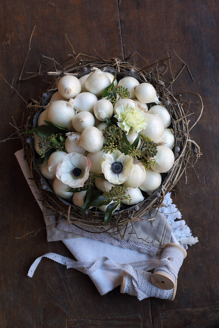 weiße Zwiebeln, Anemonen und Efeubeeren in einem Kranz