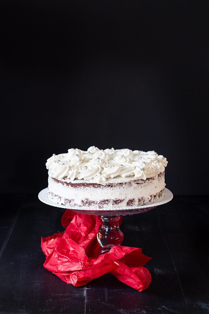 A creamy cake on a cake stand against a black background
