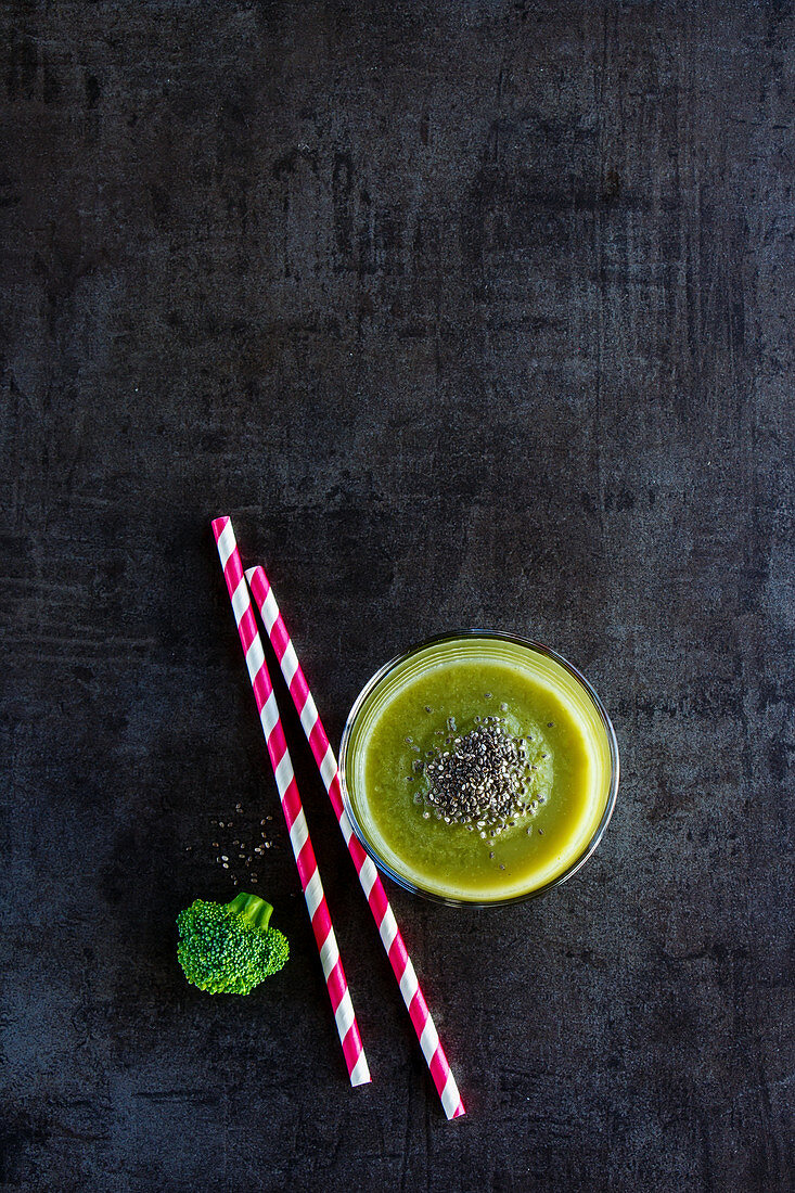 Glass filled with fresh green smoothie on dark concrete table