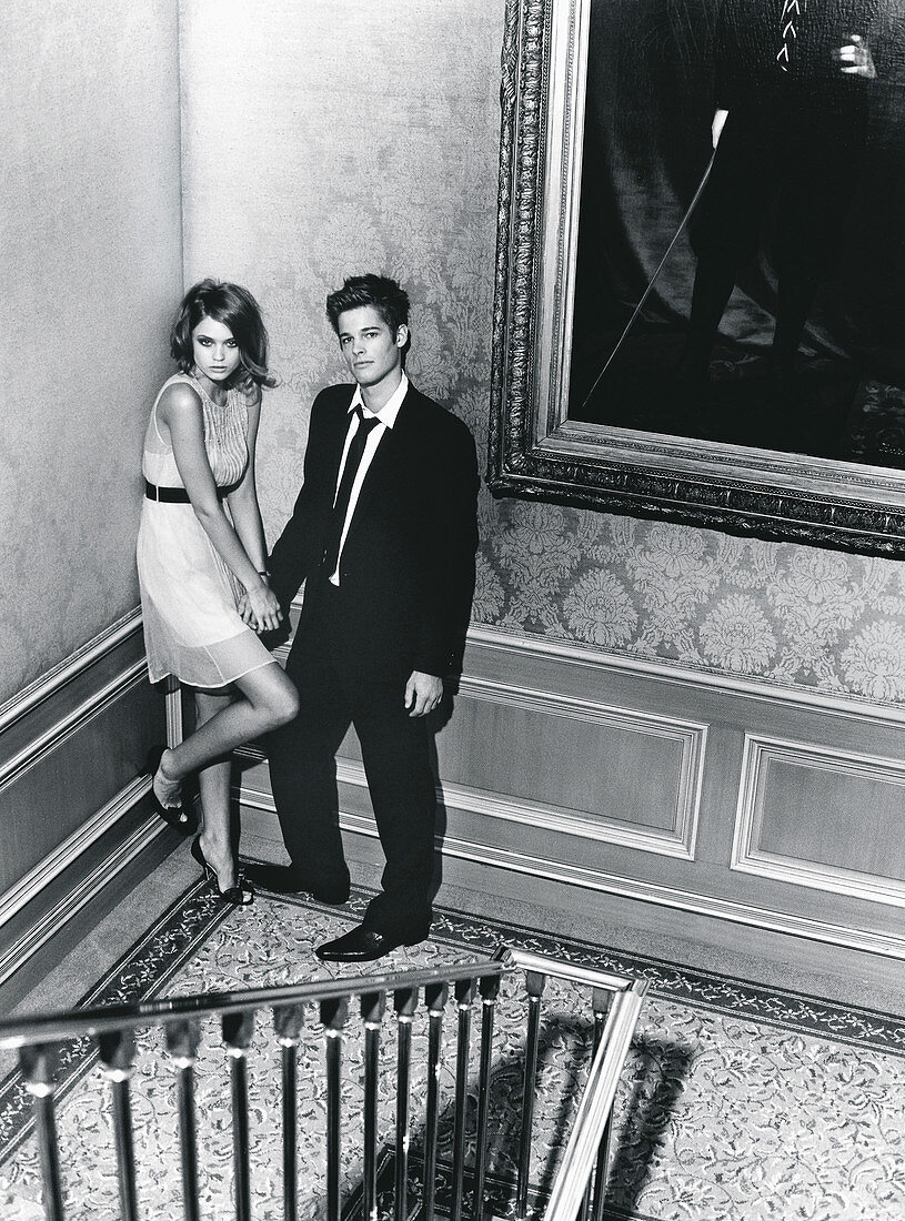 Elegant gekleidetes, junges Paar im Treppenhaus (s-w-Aufnahme)