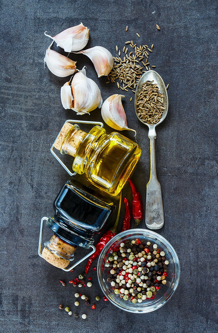 An arrangement of ingredients: vinegar, oil, garlic and spices (seen from above)