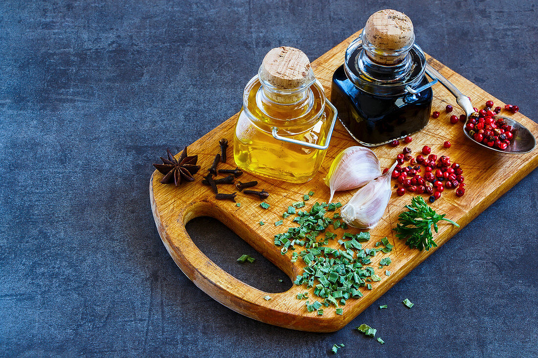 Vinegar, oil, herbs and spices on a vintage wooden board