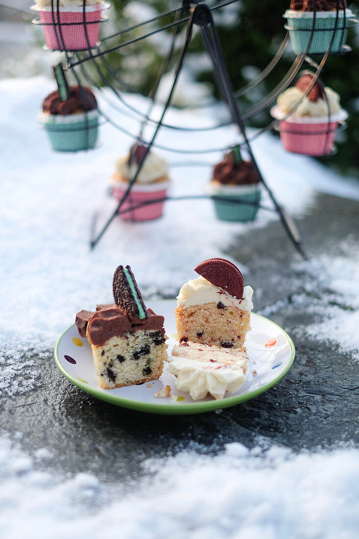 Verschiedene Cupcakes auf Teller und Cupcake-Ständer im Schnee