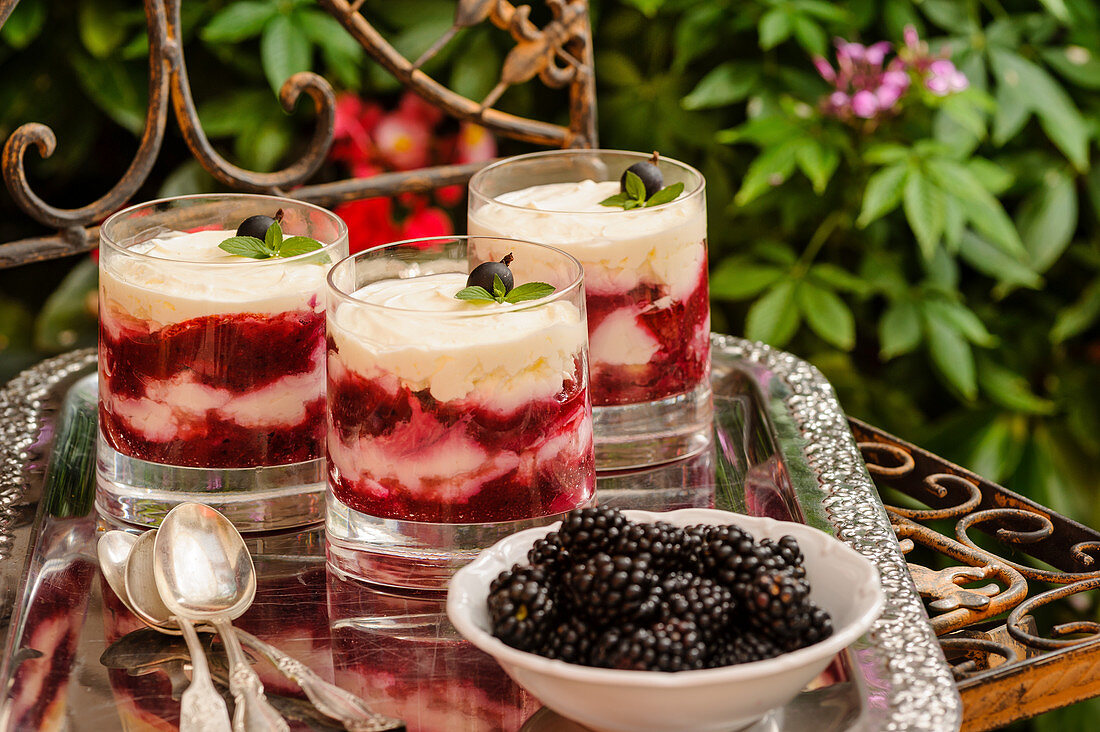 Glasses of berry tiramisu and a bowl of blackberries