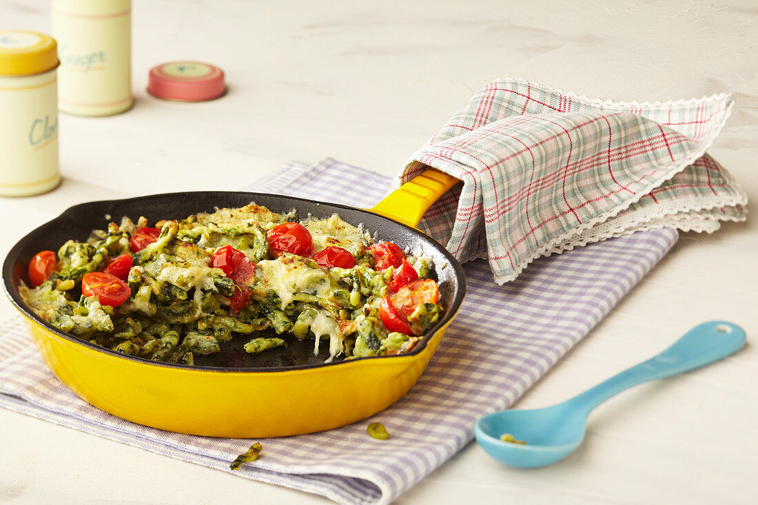 Gratinated spinach egg noodles with tomatoes in a pan