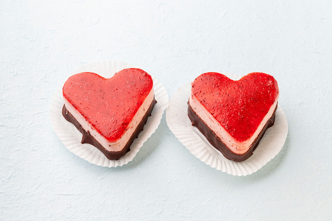 Two heart-shaped strawberry cream tarts on a white background
