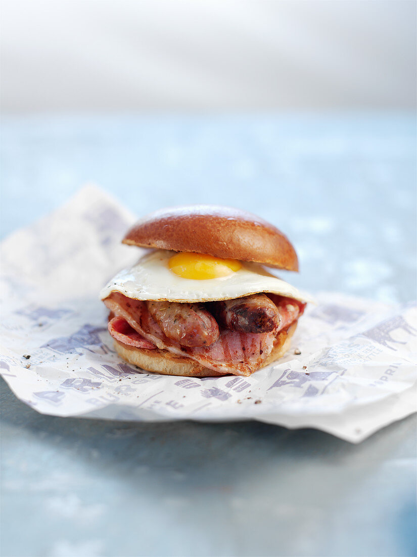 A burger with bratwurst, bacon and a fried egg