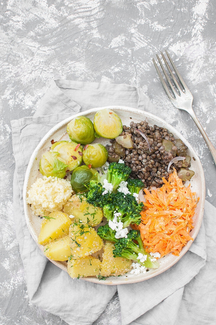 Buddha-Bowl mit Hirse, Kohl, Linsen, Feta, Kartoffeln, Karotten und Sonnenblumenkernen