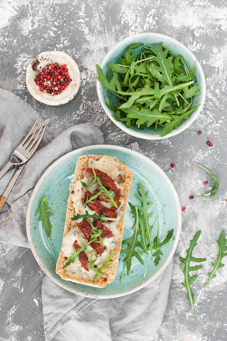 Gorgonzola-Toast mit getrockneten Tomaten, Rucola und rosa Pfeffer