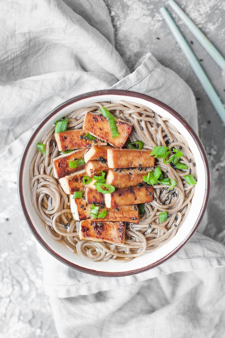 Easy miso soup with soba noodles and fried tofu, sprinkled with chopped spring onion and black sesame seeds