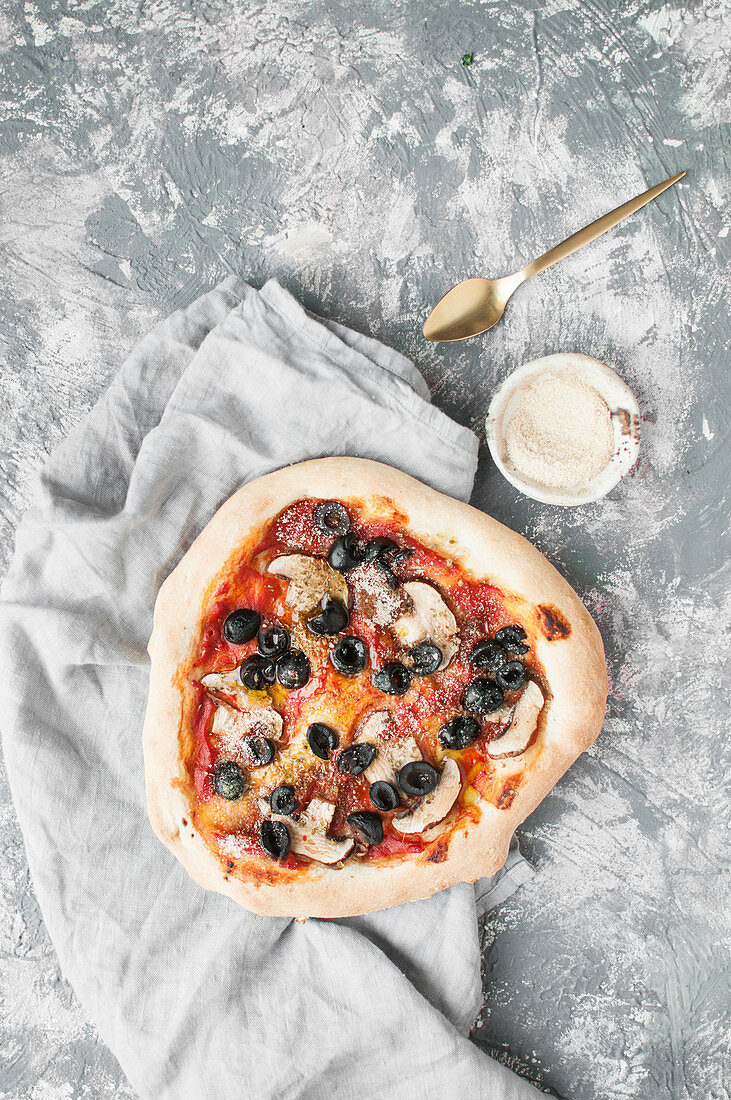 Vegan pizza with mushrooms, black olives served with yeast flakes