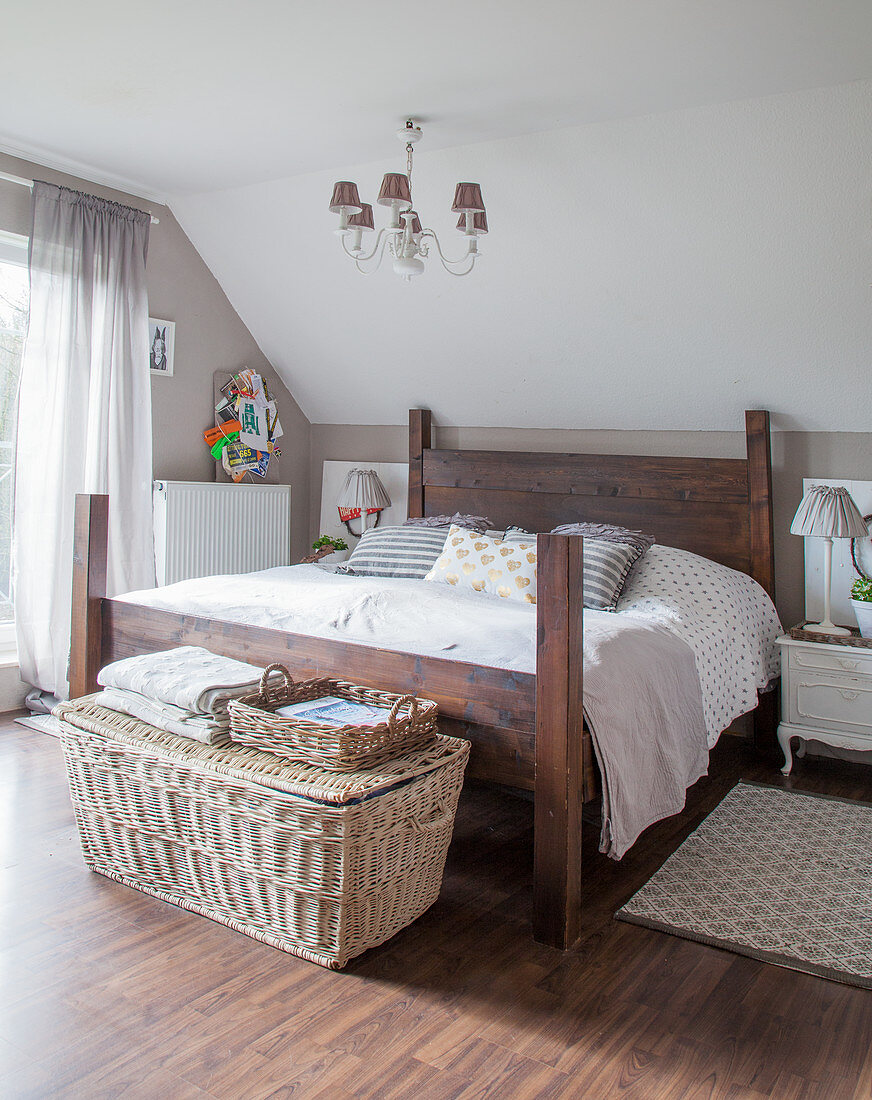 Selbst gebautes Holzbett, Nachtkästchen und Korbtruhe im Schlafzimmer