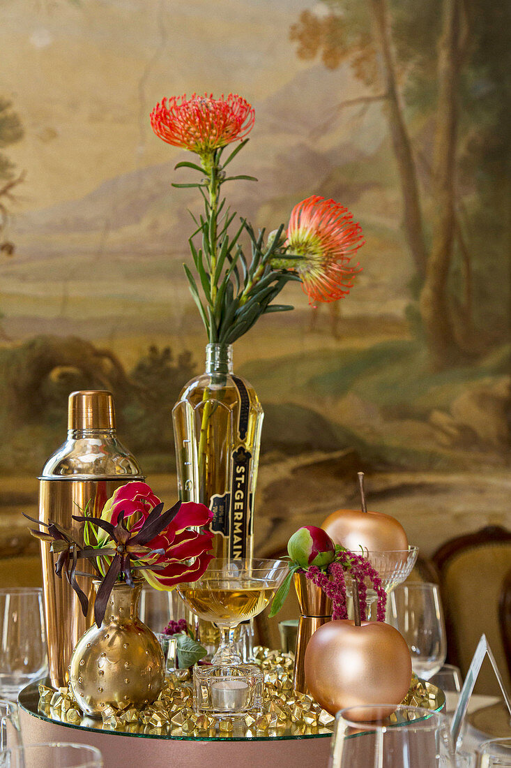 Table decoration in gold tones and proteas on a mirrored pedestal