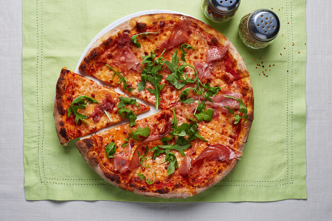 Eine Holzofenpizza mit Schinken und Rucola (Aufsicht)