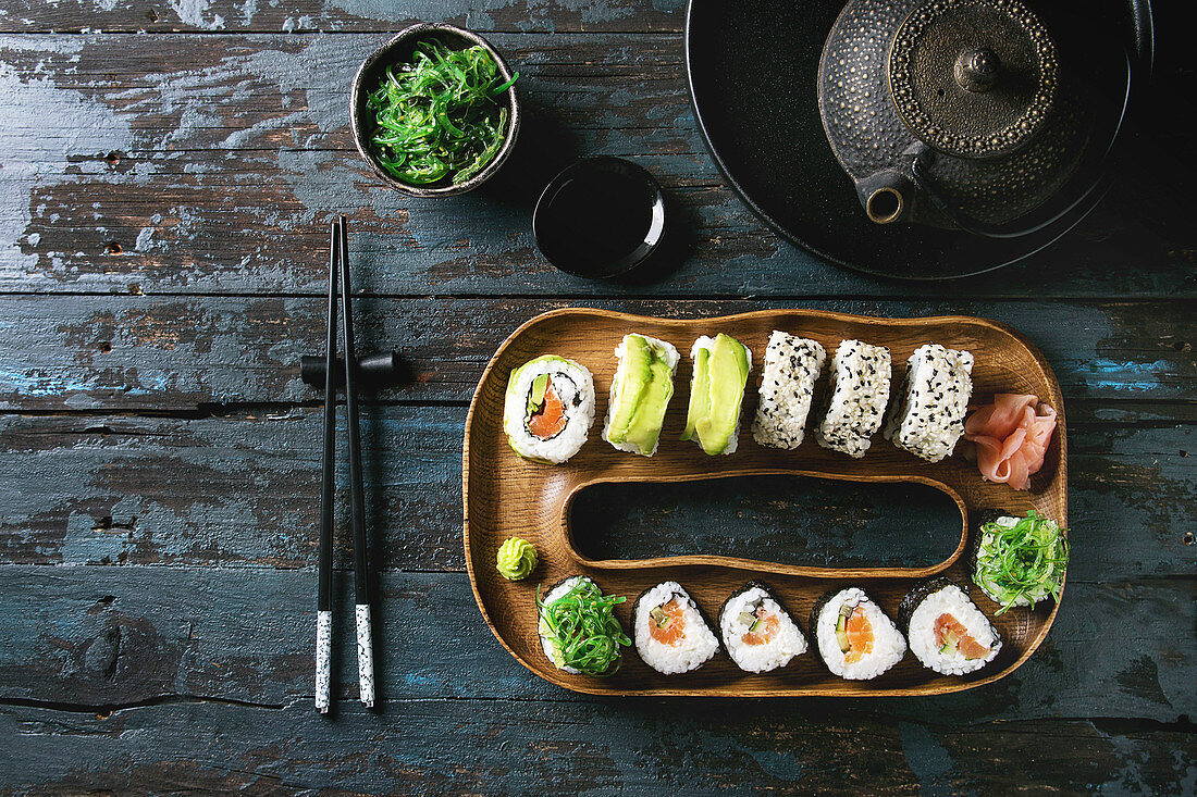Verschiedene Sushi auf ringförmiger Servierplatte und dunklem Holzuntergrund