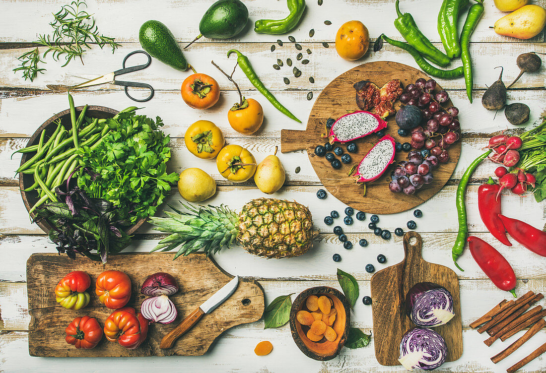 Obst, Gemüse, Kräuter und Superfoods auf Schneidebrettern und Holztisch (Aufsicht)