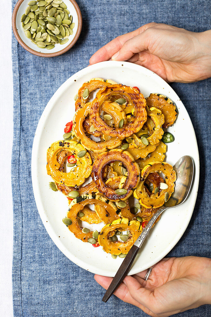 Roasted delicata squash with pumpkin seeds on a platter