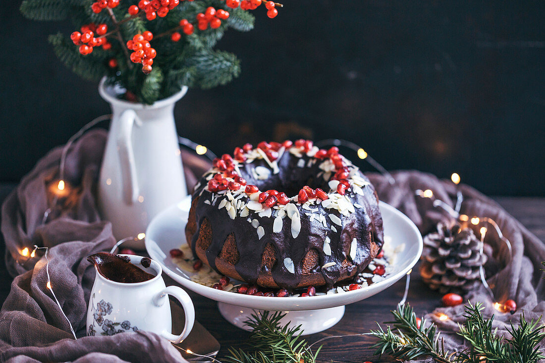 Chocolate bundt cake topped with chocolate ganache, slivered almonds and pomegranate seeds
