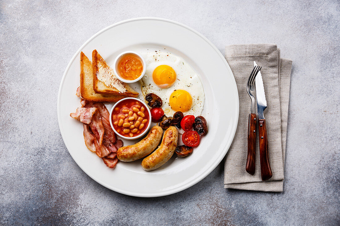 Englisches Frühstück mit Spiegelei, Wurst, Speck, Bohnen und Toast (Aufsicht)