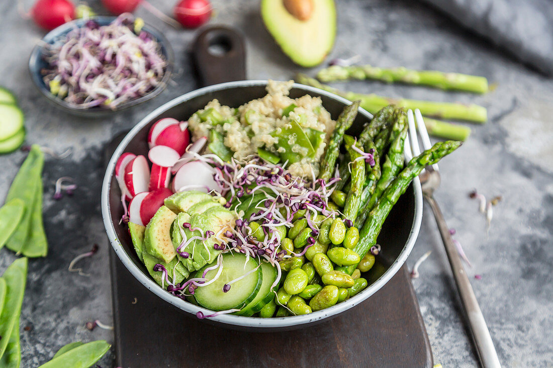 A veggie bowl with bulgur wheat, asparagus, avocado, radishes, cucumber, mangetout, edamame and red sprouts