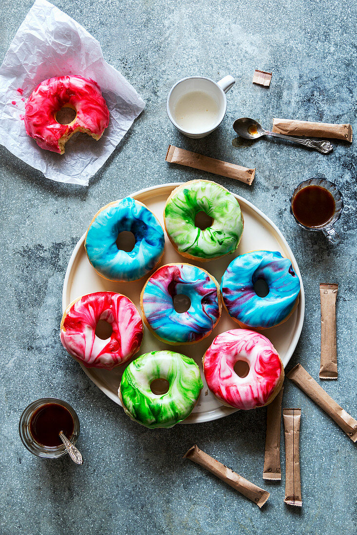 Donuts mit marmorierter grüner, roter und blauer Zuckerglasur (Aufsicht)