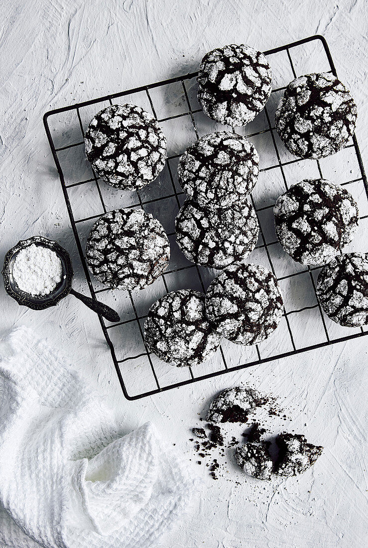 Chocolate crinkle cookies on wire cooling rack with icing sugar dusting