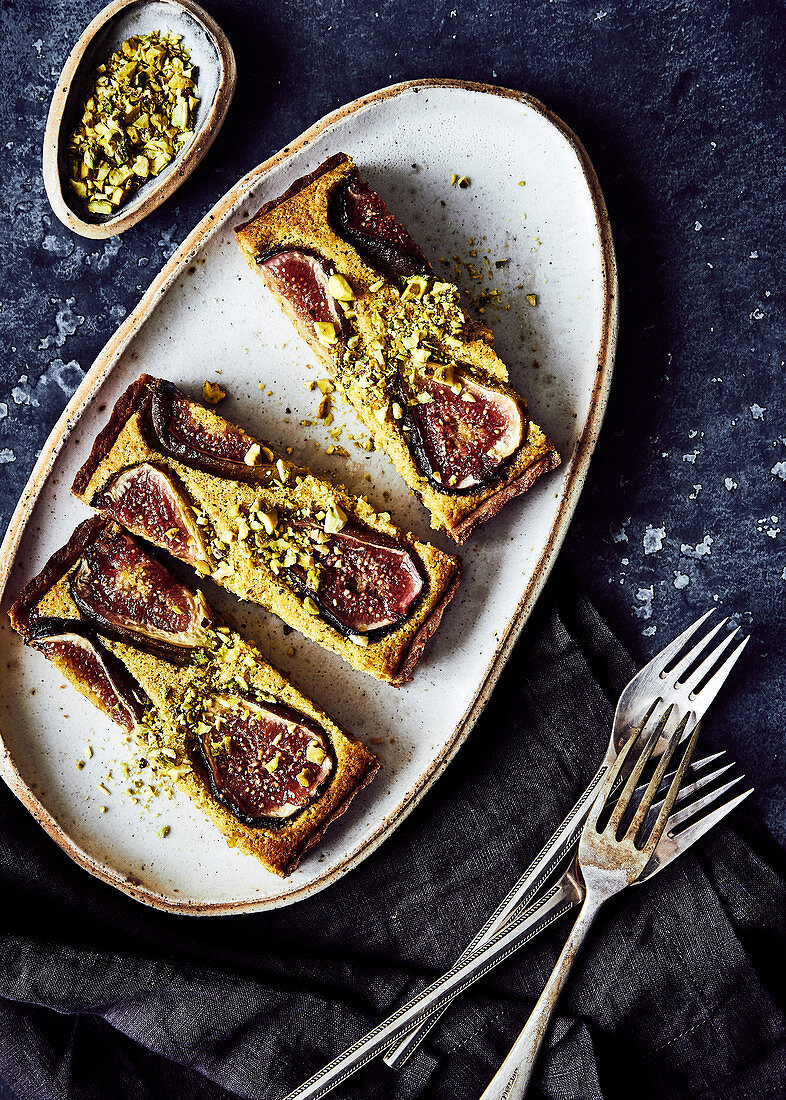 Drei Stücke Frangipane-Kuchen mit Feigen und Pistazien auf Teller