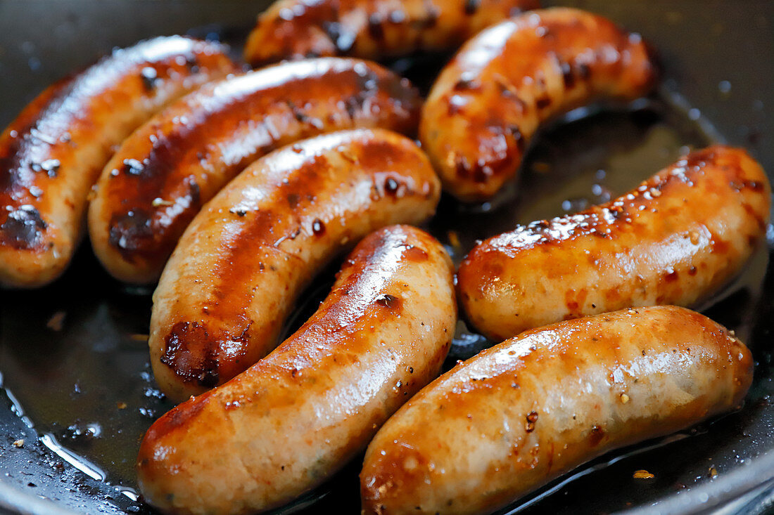 Sausages Cooking in Skillet; Tongs