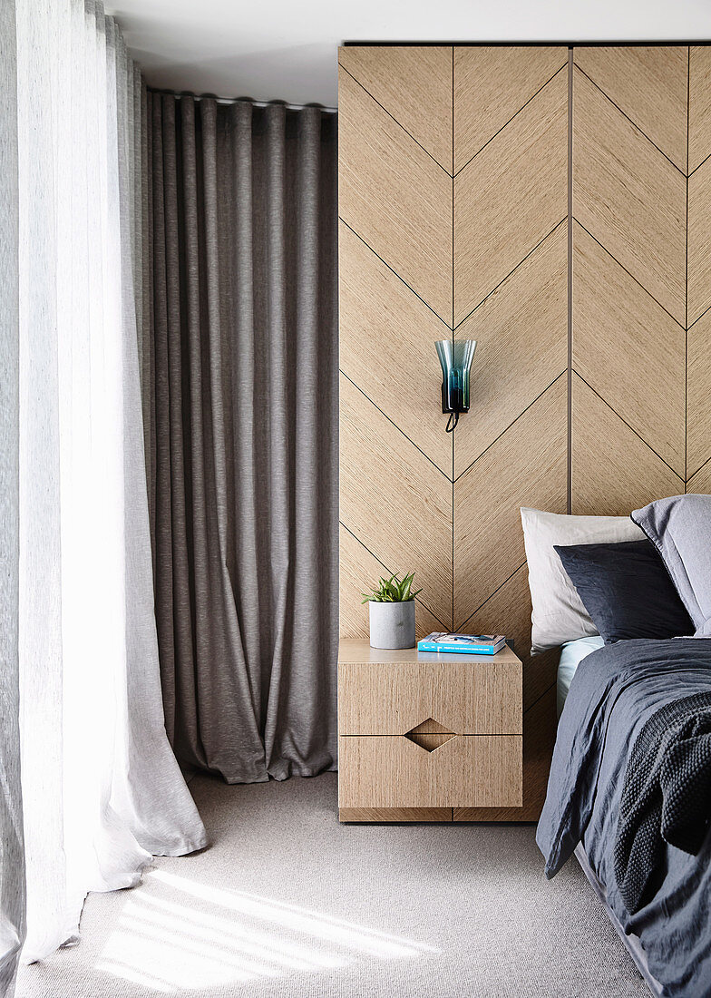 Wood veneer with an integrated bedside cabinet next to a double bed in the bedroom