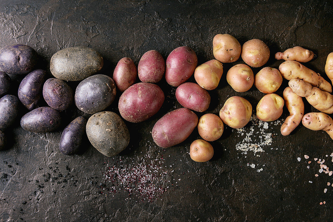 Fünf verschiedene Kartoffelsorten auf schwarzem Schieferuntergrund