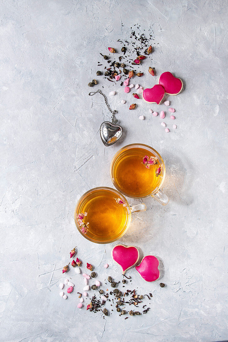 Zwei Tassen Tee mit Rosenblüten und Herzplätzchen zum Valentinstag