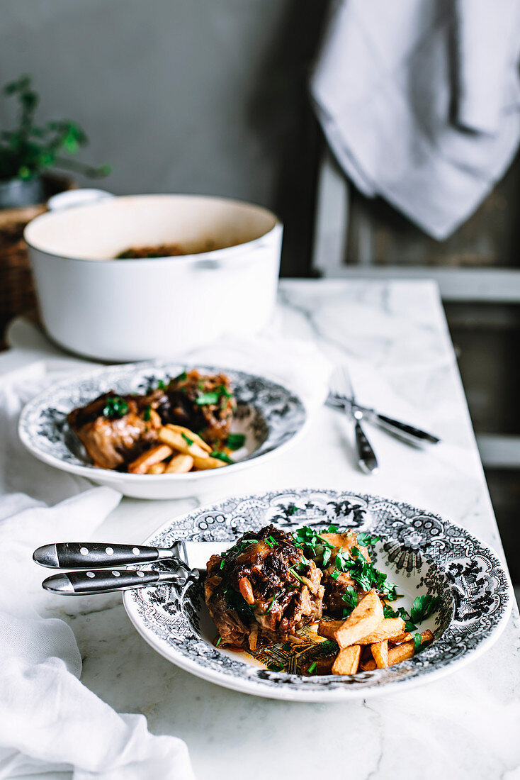 Oxtail casserole and chips on a rustic kitchen table