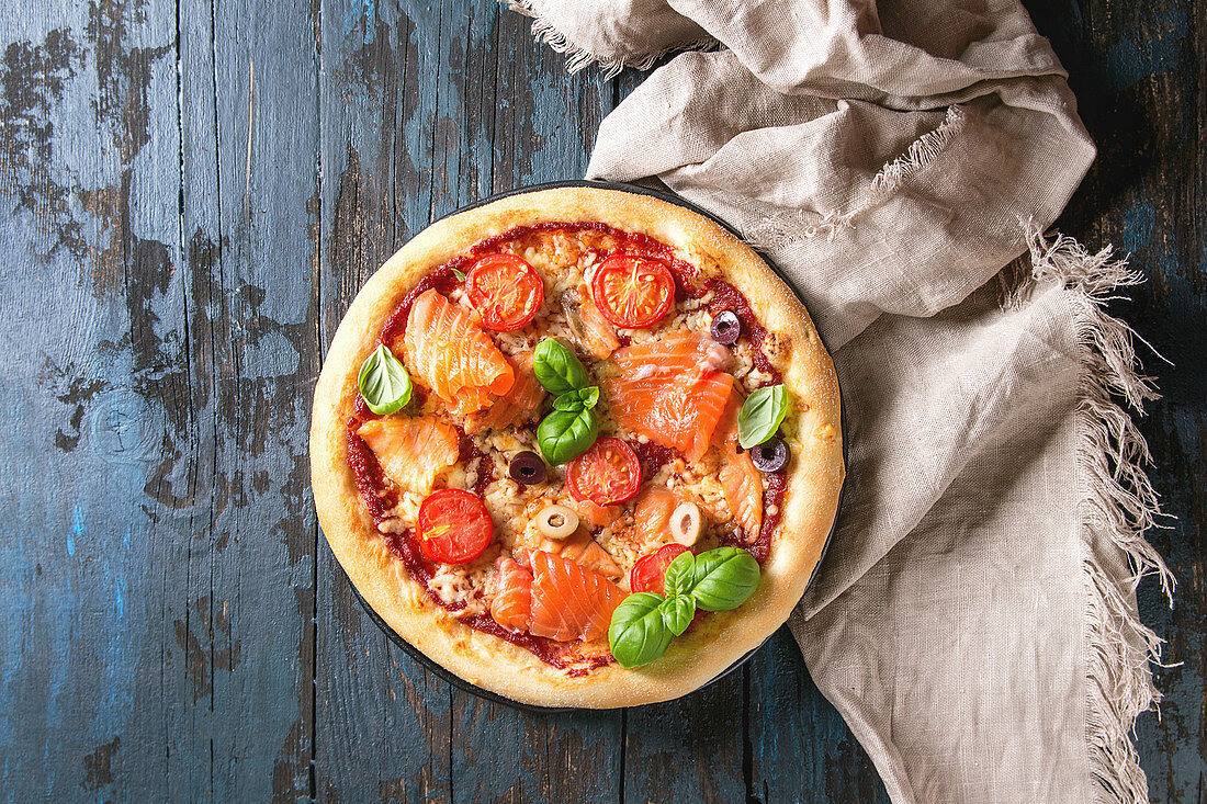 Pizza mit Räucherlachs, Tomaten, Käse und Basilikum (Aufsicht)