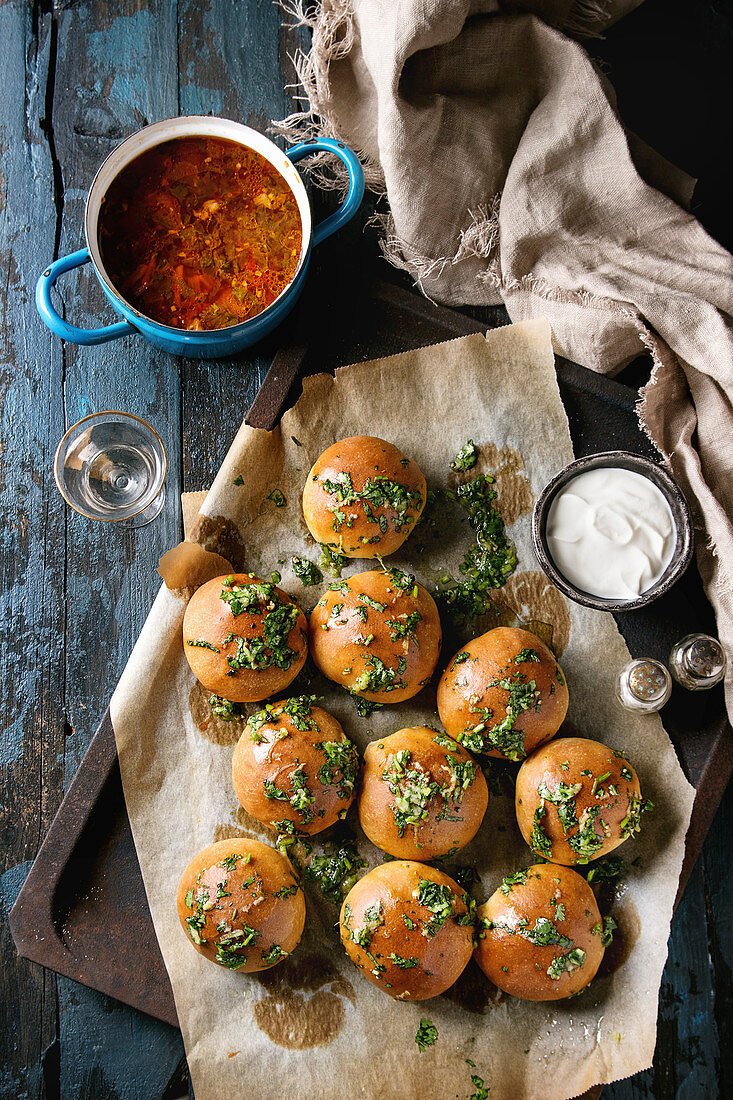 Pan of traditional beetroot borscht soup with sour cream and fresh coriander served with garlic bread buns pampushki, glass vodka