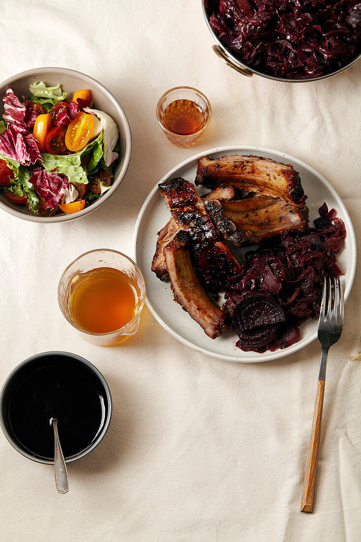 Grilled pork ribs in thick barbeque sauce garnished with red cabbage and beets braised in red wine sauce