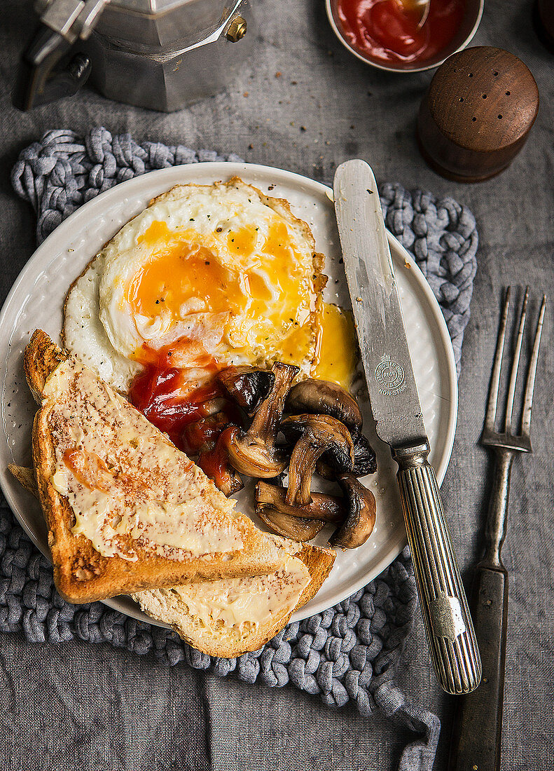 Frühstück mit Spiegelei, Pilzen, Toast und Ketchup