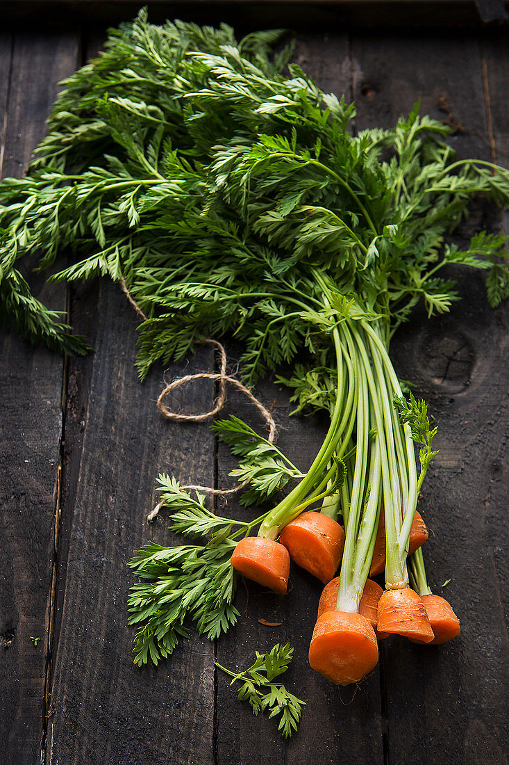 Fresh carrot tops on a wooden background
